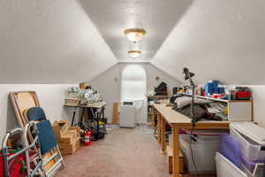 Office area with a textured ceiling, carpet floors, and vaulted ceiling