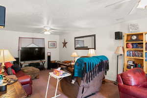 Carpeted living area with ceiling fan and baseboards