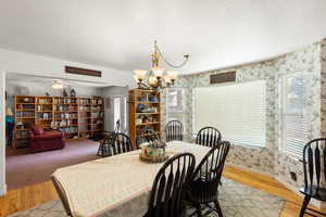 Dining area with wallpapered walls, light wood-type flooring, a chandelier, and healthy amount of natural light