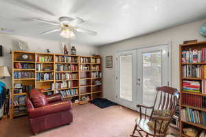 Living area featuring french doors, carpet flooring, and ceiling fan