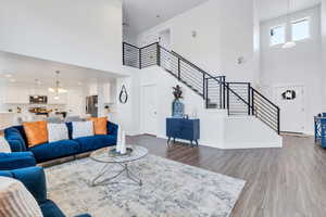 Living room featuring a towering ceiling, wood finished floors, stairs, and a chandelier