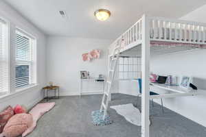 Carpeted bedroom with an office area and baseboards