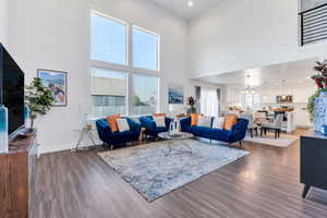 Living room featuring a towering ceiling, wood finished floors, a chandelier, and recessed lighting