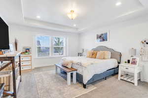 Bedroom featuring a tray ceiling, light colored carpet, and recessed lighting