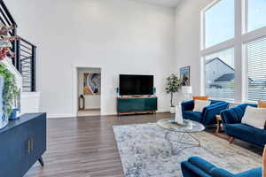 Living area with a towering ceiling, healthy amount of natural light, and wood finished floors