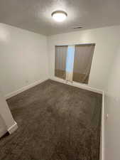 Unfurnished room with dark colored carpet and a textured ceiling