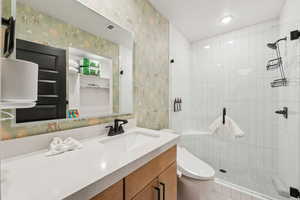 Full bath featuring wallpapered walls, a stall shower, and vanity