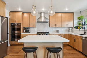 Kitchen with a breakfast bar area, stainless steel appliances, backsplash, light countertops, and light wood finished floors