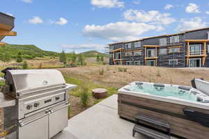 View of patio with a hot tub and grilling area