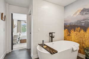 Bathroom with tile patterned flooring, a freestanding bath, and tile walls
