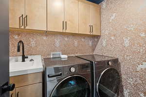 Laundry area featuring separate washer and dryer and cabinet space