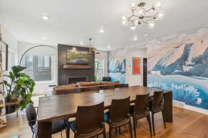 Dining area with a large fireplace, light wood-type flooring, a chandelier, and recessed lighting