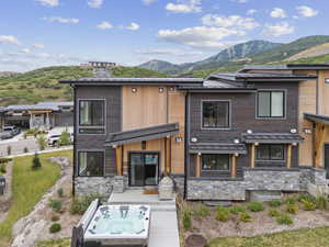 View of front of house featuring a mountain view, stone siding, a metal roof, and a standing seam roof