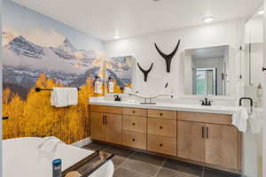 Full bath with double vanity, tile patterned flooring, and a freestanding bath