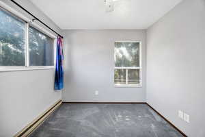 Carpeted empty room with a baseboard heating unit and ceiling fan