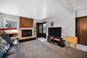 Carpeted living area with a textured ceiling, a fireplace, and tile patterned floors