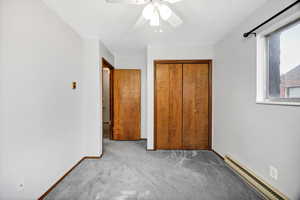 Unfurnished bedroom with baseboard heating, carpet, a closet, a ceiling fan, and a textured ceiling