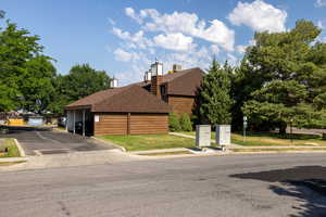 View of front facade with a front lawn, roof with shingles, and covered parking
