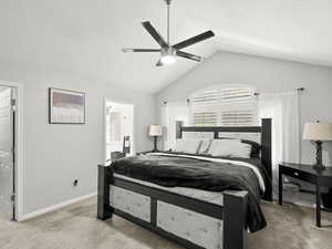 Main floor primary bedroom with vaulted ceiling, a ceiling fan, plantation shutters and a textured ceiling