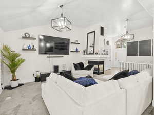 Living area with a chandelier, carpet, vaulted ceiling, and a gas fireplace