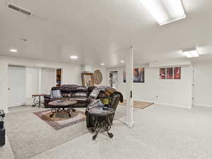 Living room with carpet, a textured ceiling, and recessed lighting