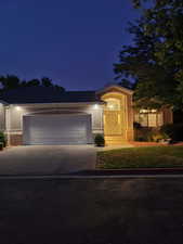 Front view of updated twin home at dusk, featuring driveway, an attached 2-car garage, and stucco & brick. Sits on a quiet dead-end lane within The Ridge community.