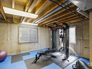 Bedroom 4 in the basement, unfinished, with utility sink and built-in workbench, closet, 2 windows; currently used as home gym.