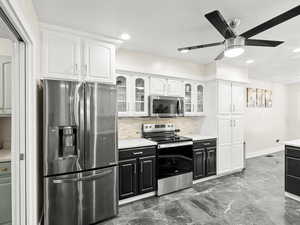 Kitchen with appliances with stainless steel finishes, ceiling fan, decorative backsplash, white cabinetry, and recessed lighting