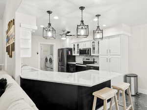 Kitchen featuring marble counter tops, appliances with stainless steel finishes, glass insert cabinets, white cabinets, and recessed lighting