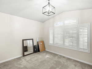 Bedroom 2 upstairs with vaulted ceiling, white plantation shutters, carpet flooring, and a chandelier