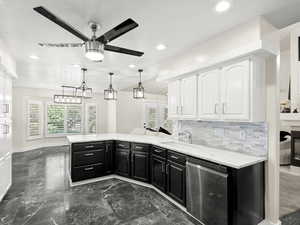 Kitchen with dark cabinets, white cabinets, ceiling fan, stainless steel dishwasher, and dark marble finish floors