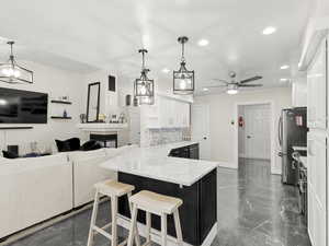Kitchen with recessed lighting, white cabinets, marble counter tops, tasteful backsplash, and a peninsula