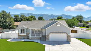 View of front of house with covered porch, concrete driveway, a garage, a mountain view, and brick siding