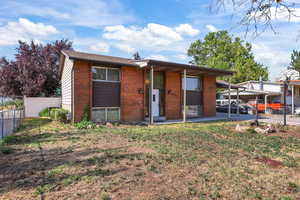 View of front of house featuring brick siding and a carport