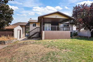 View of front of house with a front lawn, a storage shed, a chimney, and stairs