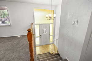 Foyer with a chandelier, a textured wall, and stairway