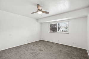 Carpeted empty room with ceiling fan and baseboards