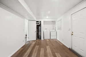 Laundry room with washing machine and clothes dryer, wood finished floors, and gas water heater