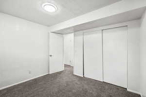 Unfurnished bedroom with carpet, a closet, and a textured ceiling