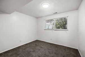 Carpeted spare room with a textured ceiling and baseboards