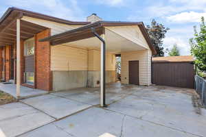 View of side of property featuring driveway, a chimney, and a carport
