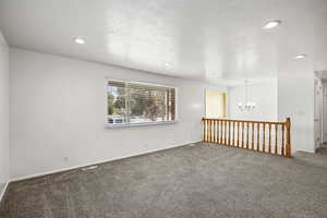 Spare room featuring a chandelier, carpet, and recessed lighting