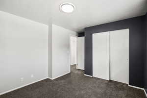 Unfurnished bedroom with dark colored carpet and a closet