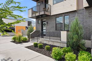 Entrance to property featuring a balcony and brick siding