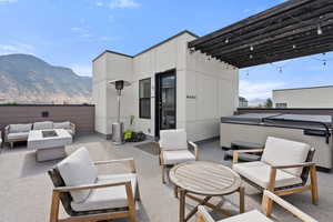 View of patio / terrace featuring a hot tub, a mountain view, an outdoor living space with a fire pit, and a pergola