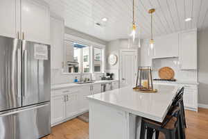 Kitchen featuring freestanding refrigerator, wood ceiling, light countertops, a center island, and backsplash