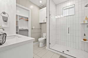 Bathroom featuring vanity, a shower stall, tile patterned flooring, and a walk in closet