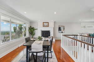 Dining space featuring a glass covered fireplace, hardwood / wood-style flooring, recessed lighting, and crown molding