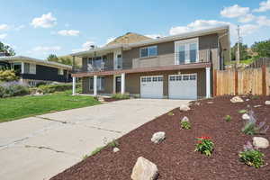 View of front of home featuring a balcony, driveway, brick siding, and a garage