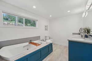 Full bathroom with double vanity, a whirlpool tub, and recessed lighting